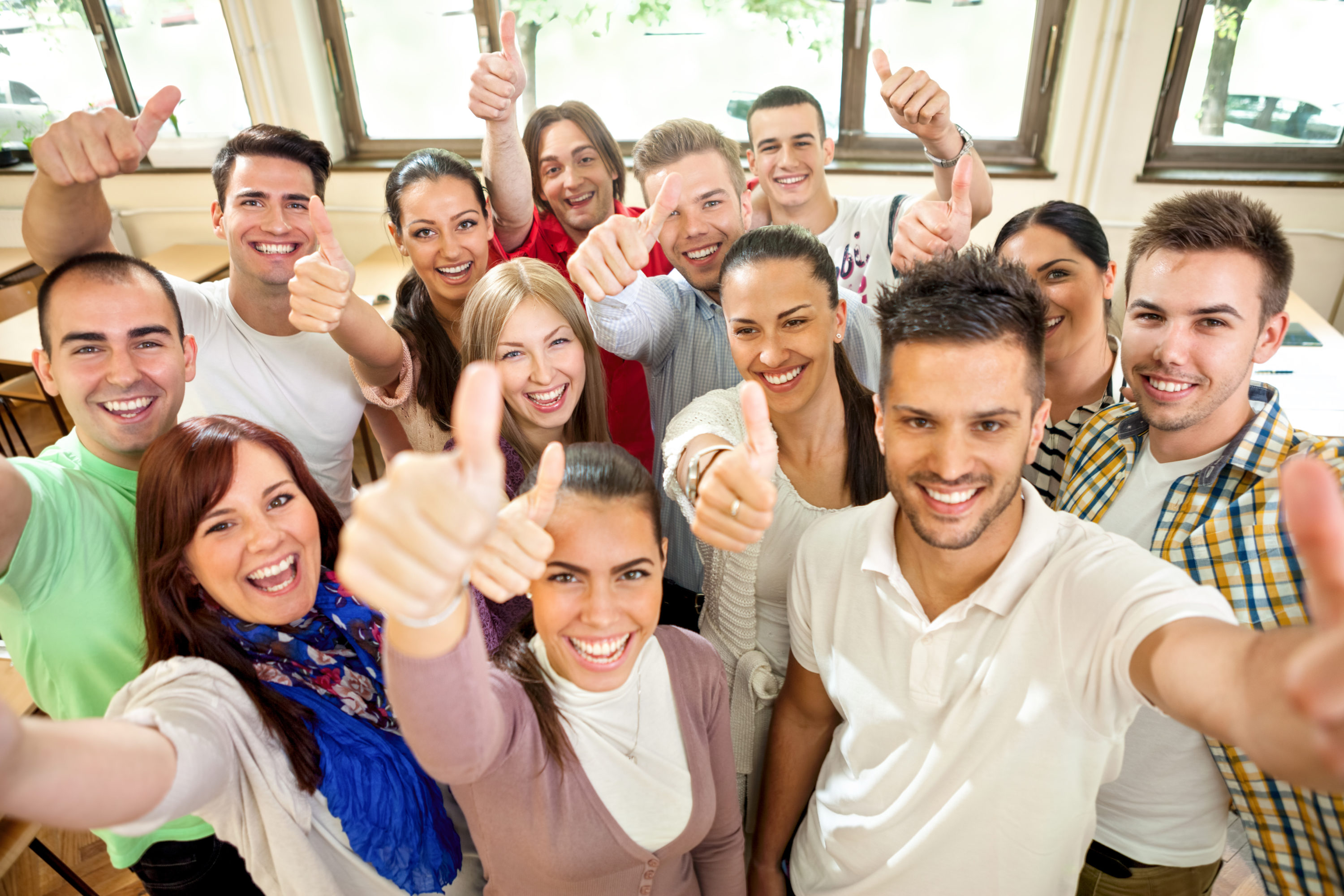 Group of people smile for the camera and showing thumbs up